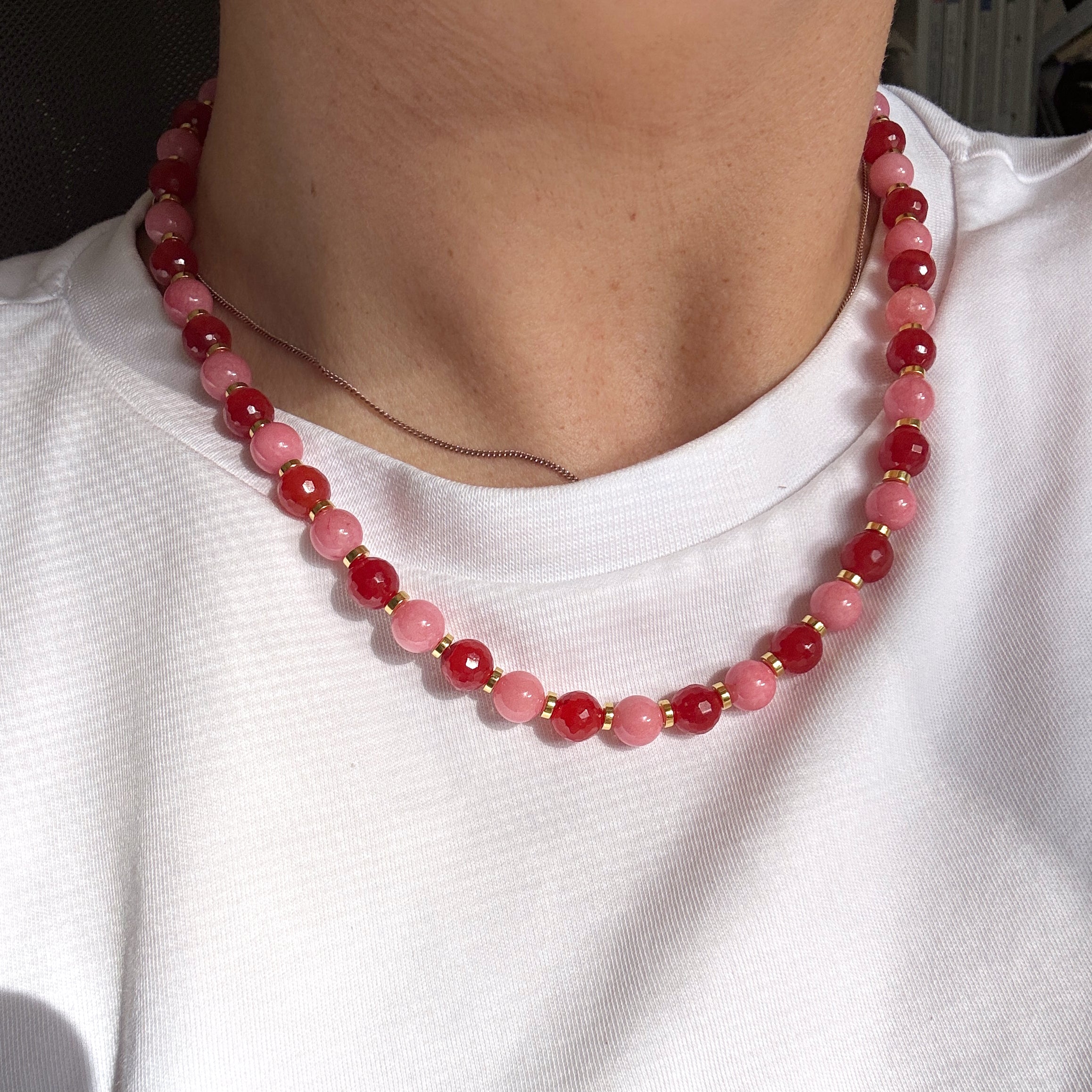 Close-up of a necklace with red and pink beads on a person's necklace