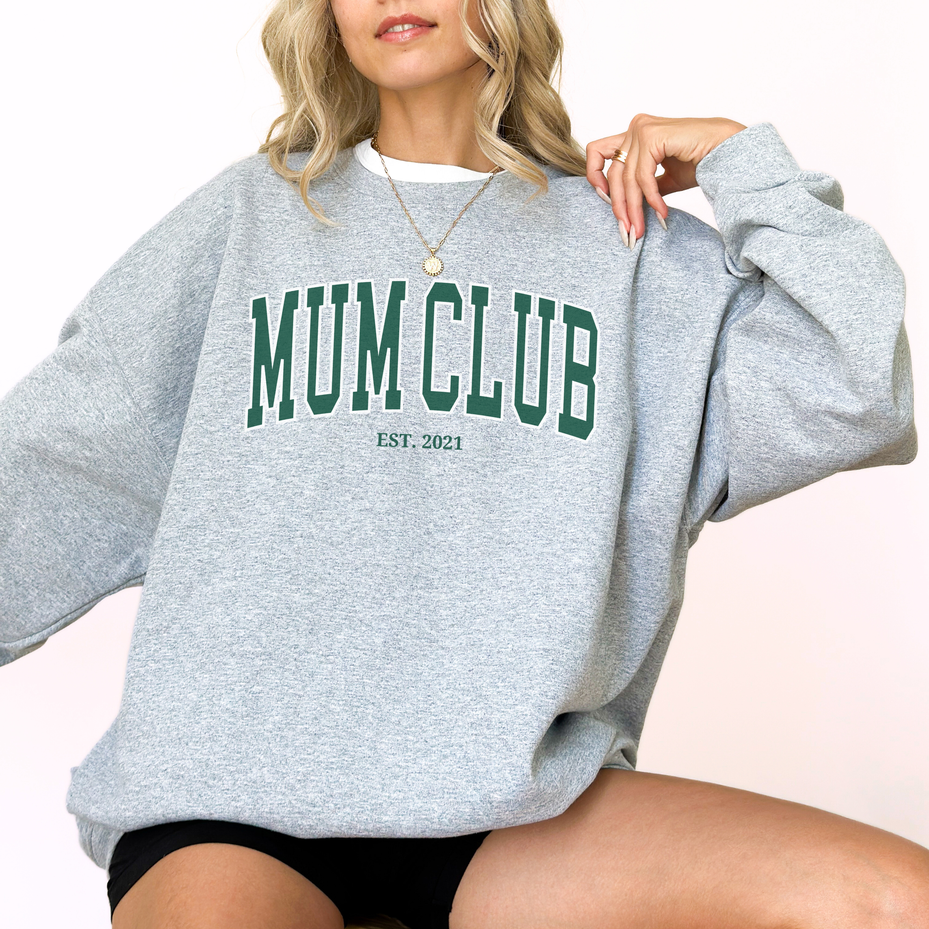 Person wearing a gray sweatshirt with 'MUM CLUB EST. 2021' text on a white background