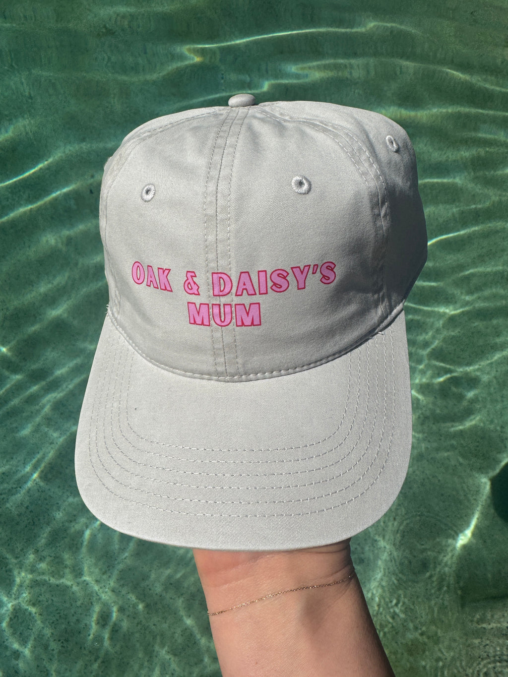 Gray cap with pink text held above green water