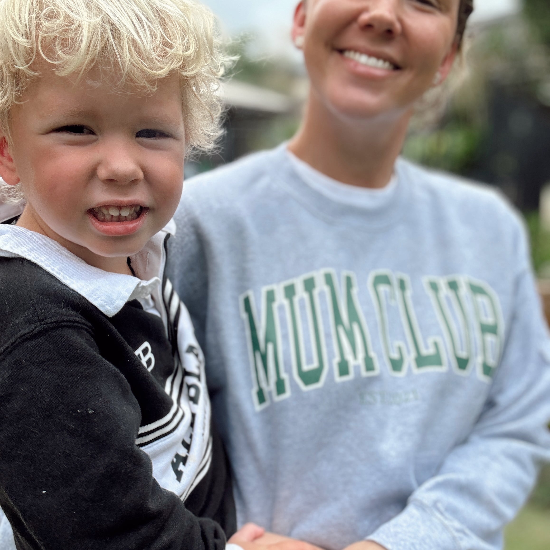 Child and adult wearing a 'MUM CLUB' sweatshirt outdoors