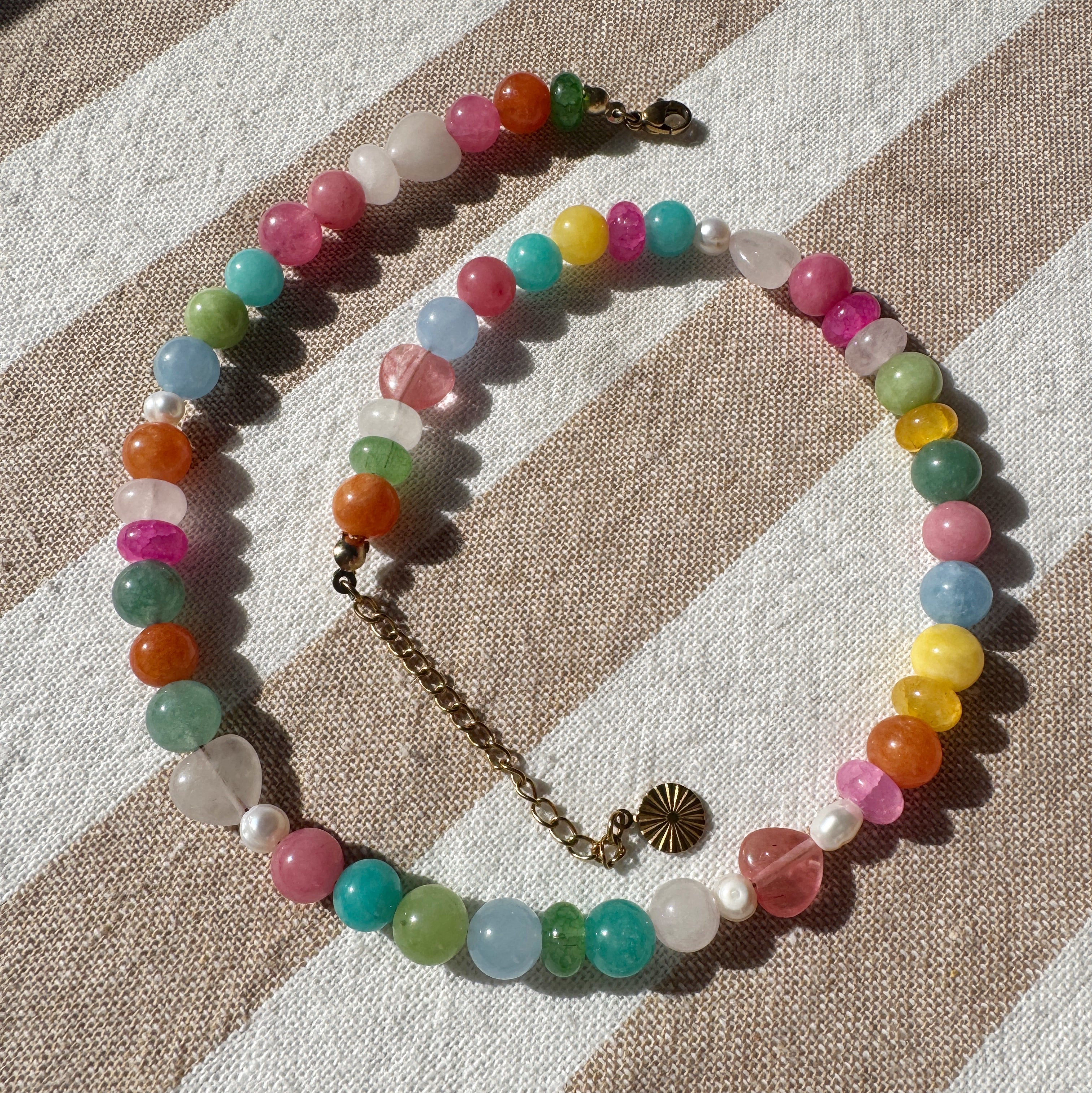 Colorful beaded necklace on a striped fabric background