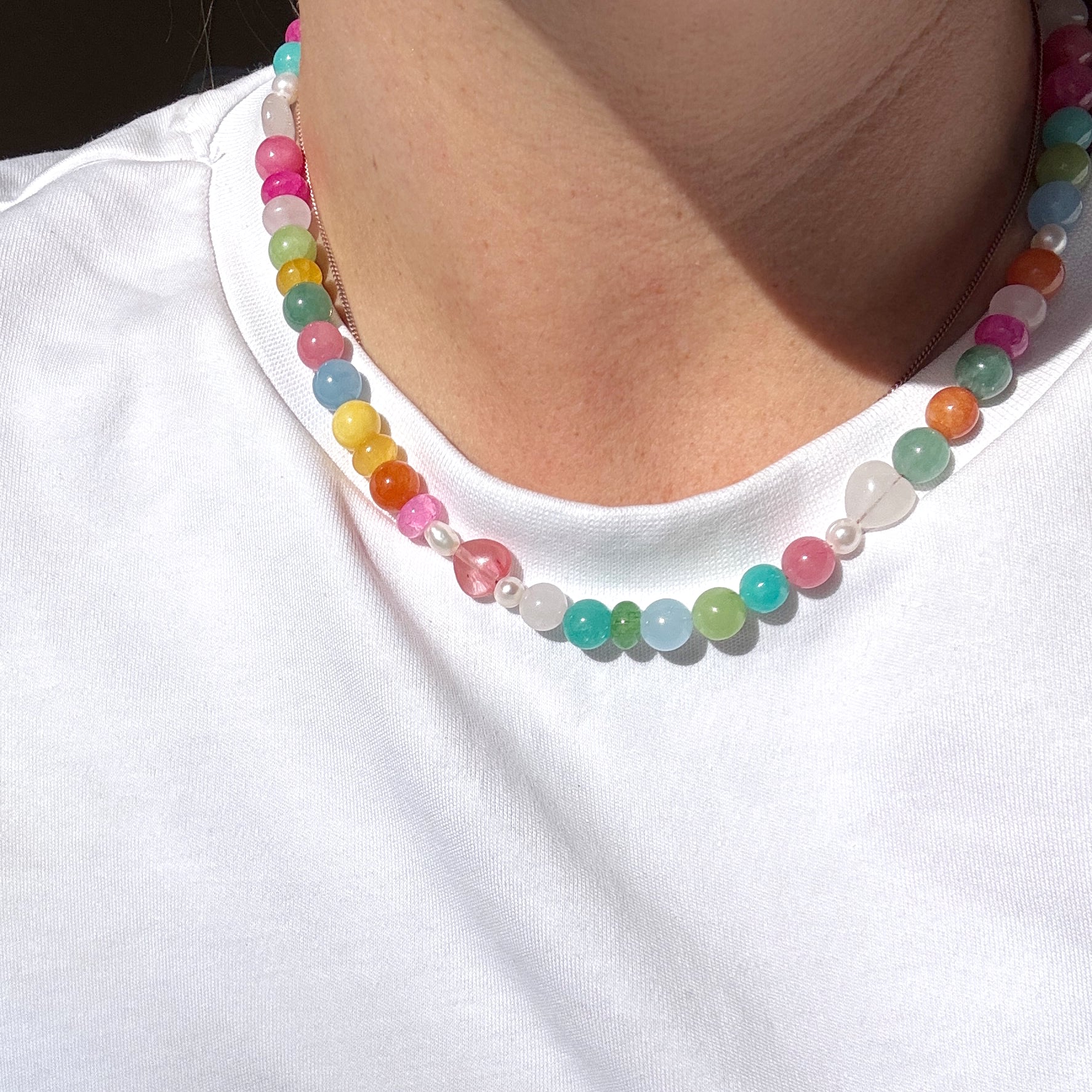 Colorful beaded necklace worn by a person on a white background