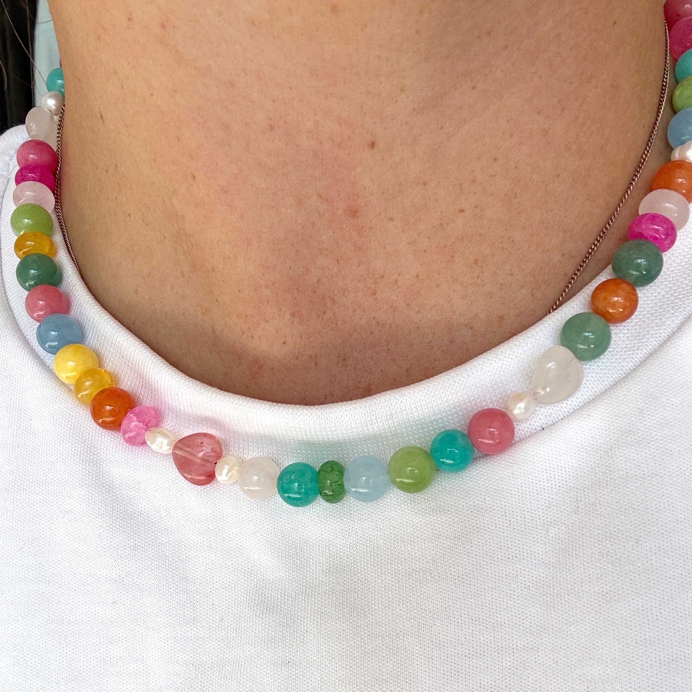Colorful beaded bracelet on a person's wrist against a white background